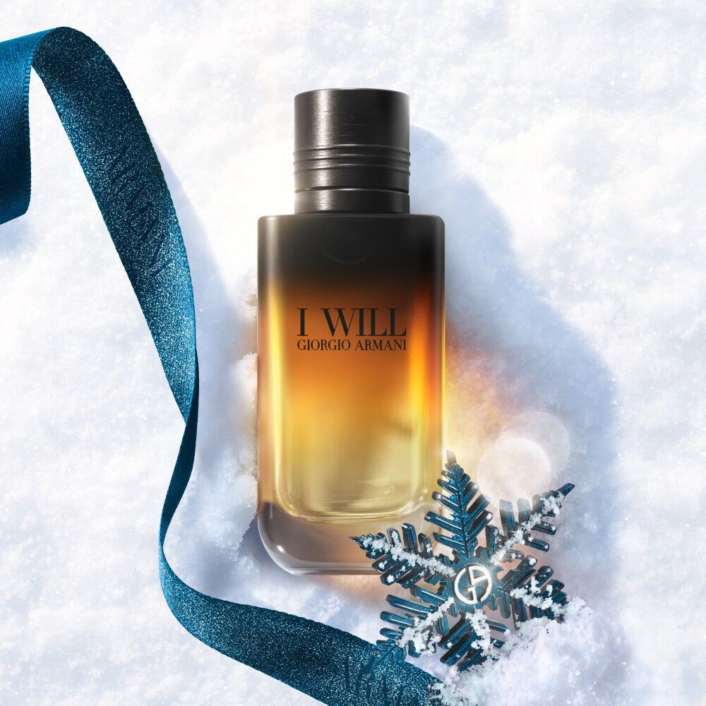 Black and amber Armani gift box with teal ribbon on a snowy surface — I Will Eau de Parfum men's fragrance gift set, holiday gifting visual.