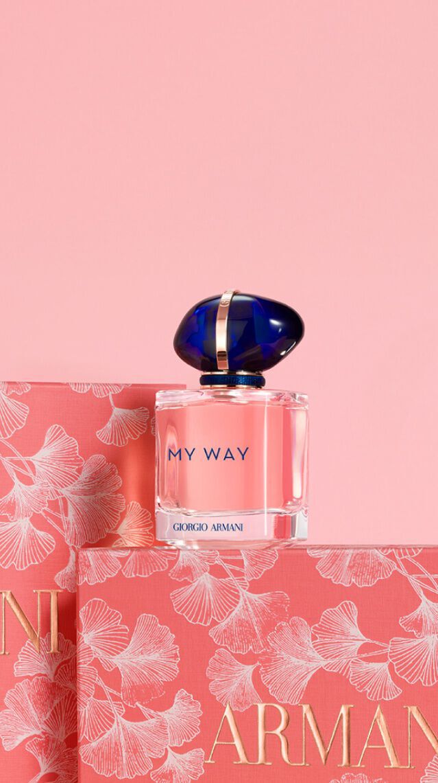 Ein Parfumflakon von Armani steht auf einer stilvollen, blushfarbenen Verpackung mit floralem Design. Der Hintergrund ist ebenfalls in sanften Rosa-Tonen gehalten.