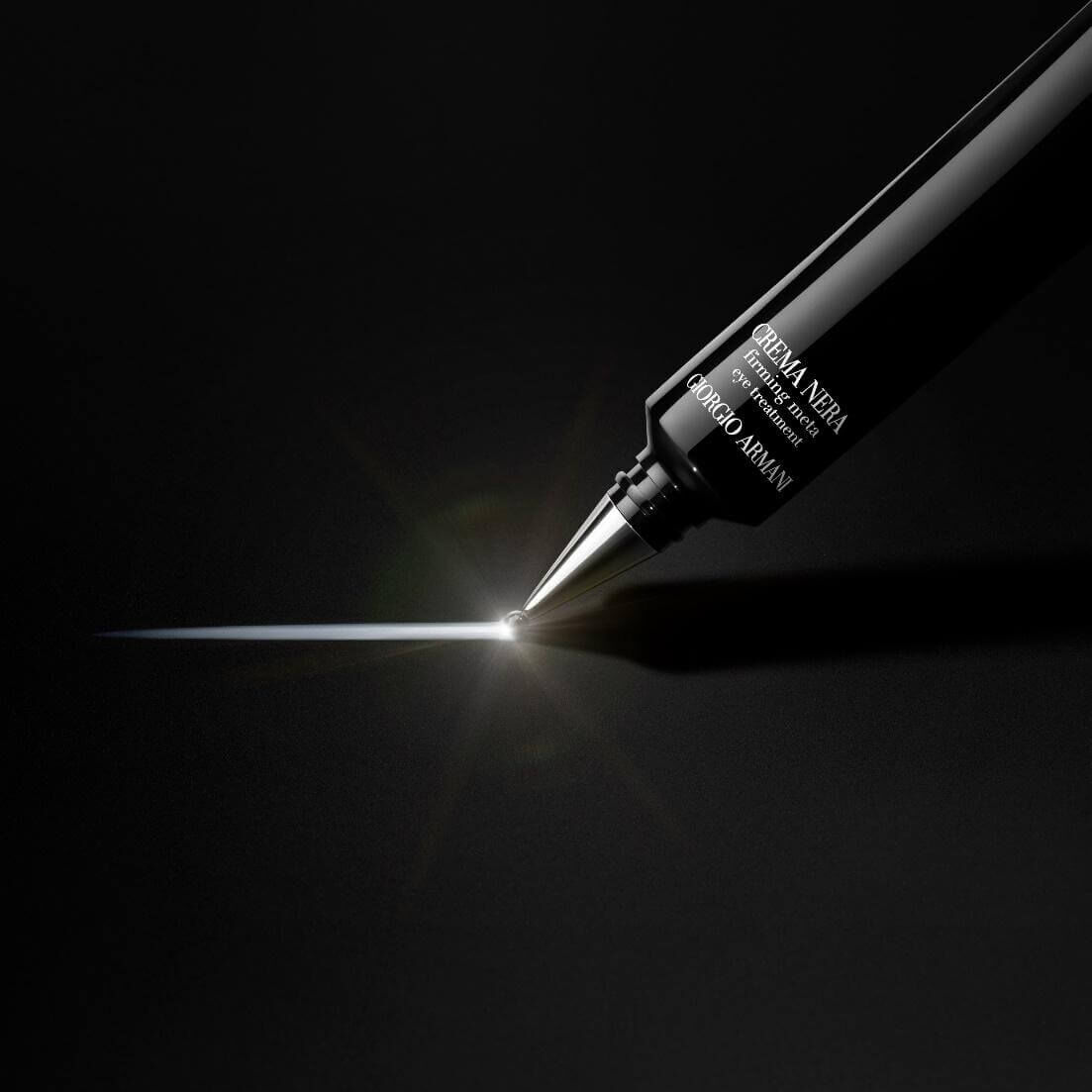 A close-up image of a black eyeliner pen with a fine tip, emitting a sharp, reflective line of product against a dark background.