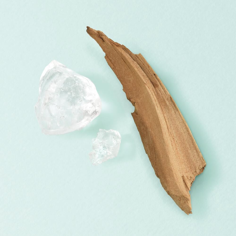 Ein Stuck Holz und zwei Kristalle liegen auf einer mintgrunen Oberflache. Minimalistisches Arrangement.