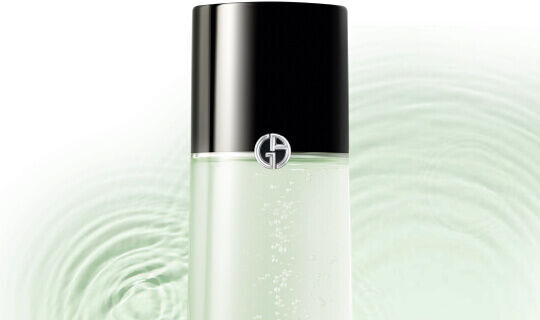 Ein eleganter Flakon mit schwarzem Deckel und einem geringen, hellen Flussigkeitsinhalts, umgeben von sanften Wasserringen.