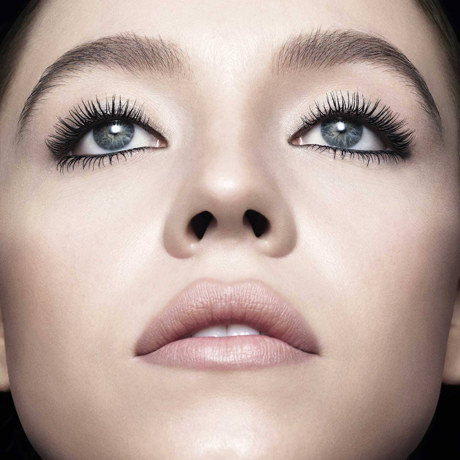 Close-up of a woman's face, showcasing her striking blue eyes, full lashes, and a soft, natural makeup look.