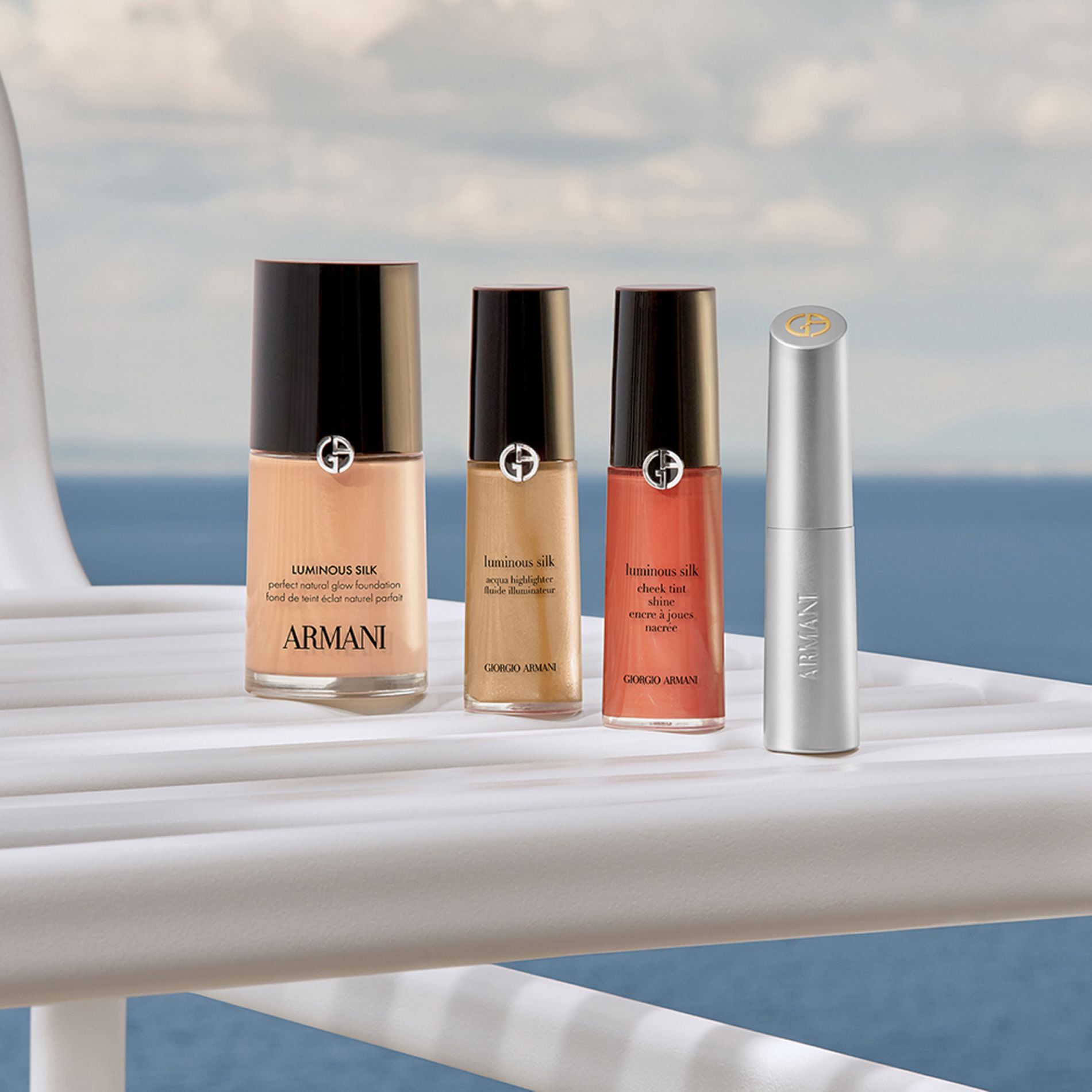 Ein edles Beauty-Ritual: Luminous Silk Foundation, Concealer, Cheek Tint und ein silberner Lippenstift. Auf einer Yacht vor dem Meer versprechen diese Ikonen ein naturliches Strahlen fur eine luxuriose Auszeit an der Kuste.