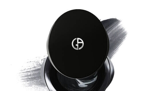 Schwarzer Puderbehalter mit dem Logo von Giorgio Armani auf einer grauen Farbflache.