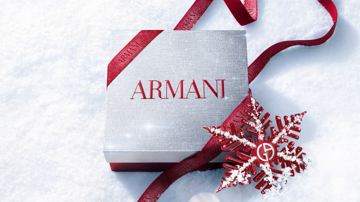 Ruby Power of You Eau de Parfum bottle with red Armani ribbon and jewelled snowflake on a snowy surface — Giorgio Armani women's fragrance, holiday gift set visual.