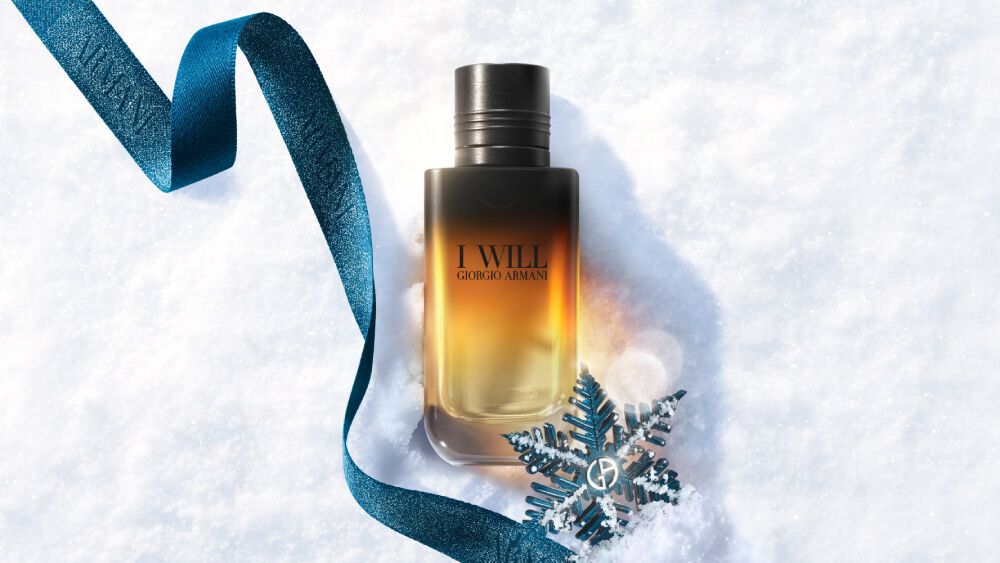 Black and amber Armani gift box with teal ribbon on a snowy surface — I Will Eau de Parfum men's fragrance gift set, holiday gifting visual.