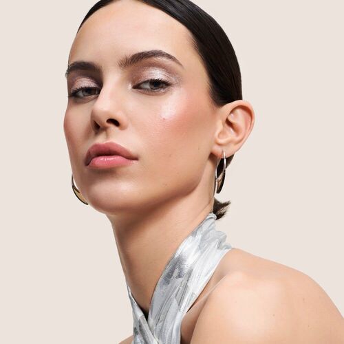 Portrat einer Frau mit elegantem Makeup und silbernem Schal vor neutralem Hintergrund.