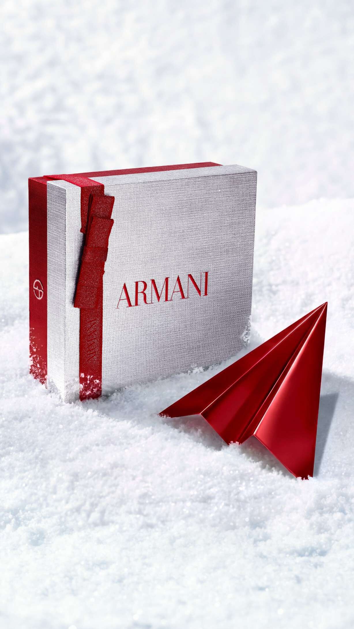 Silberne Armani Beauty Geschenkbox mit einem roten Papierflieger als Symbol fur die kostenlose Lieferung zu den Festtagen.