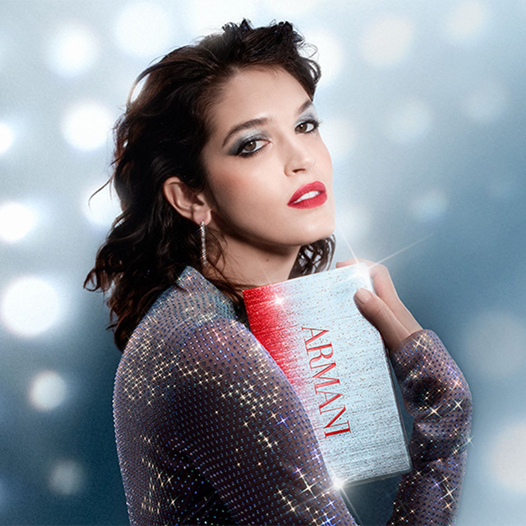 Eine schone Frau mit einem weihnachtlichen Make-up-Look halt eine Geschenkbox, vor einem Hintergrund aus traumhaften Lichtpunkten im Disco-Stil.