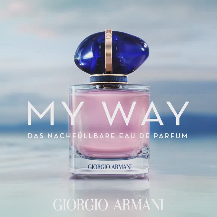 A stylish perfume bottle with a blue cap, featuring the text "MY WAY" and "THE REFILLABLE EAU DE PARFUM," along with the Giorgio Armani logo, set against a serene background.