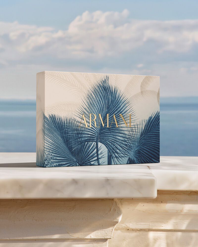 Ein luxurioses Armani Geschenkset mit blauem Botanik-Muster auf Marmor vor dem Meer. Eine Hommage an die „Armani Mare“-Kollektion, die Couture-Handwerkskunst mit sonnendurchfluteter Eleganz und Raffinesse verbindet.