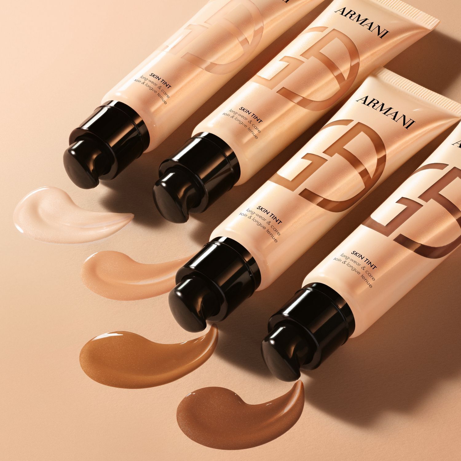 Vier Armani Skin Tint Tuben mit aufgetragenen Swatches, die eine Reihe von Farbtonen zeigen.
