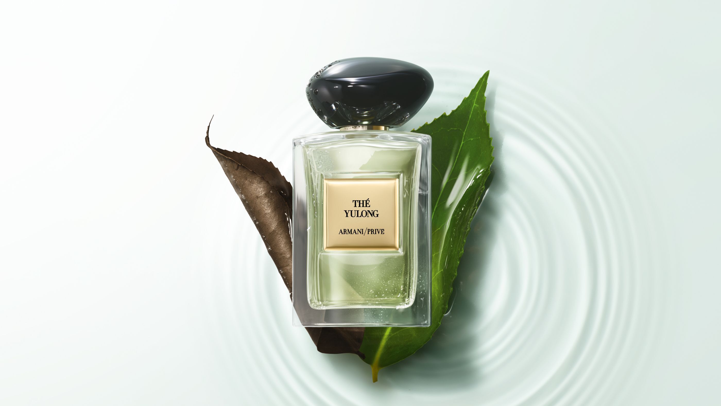Parfumflakon Armani/Prive „The Yulong“ auf Blattern uber gewelltem Wasser.