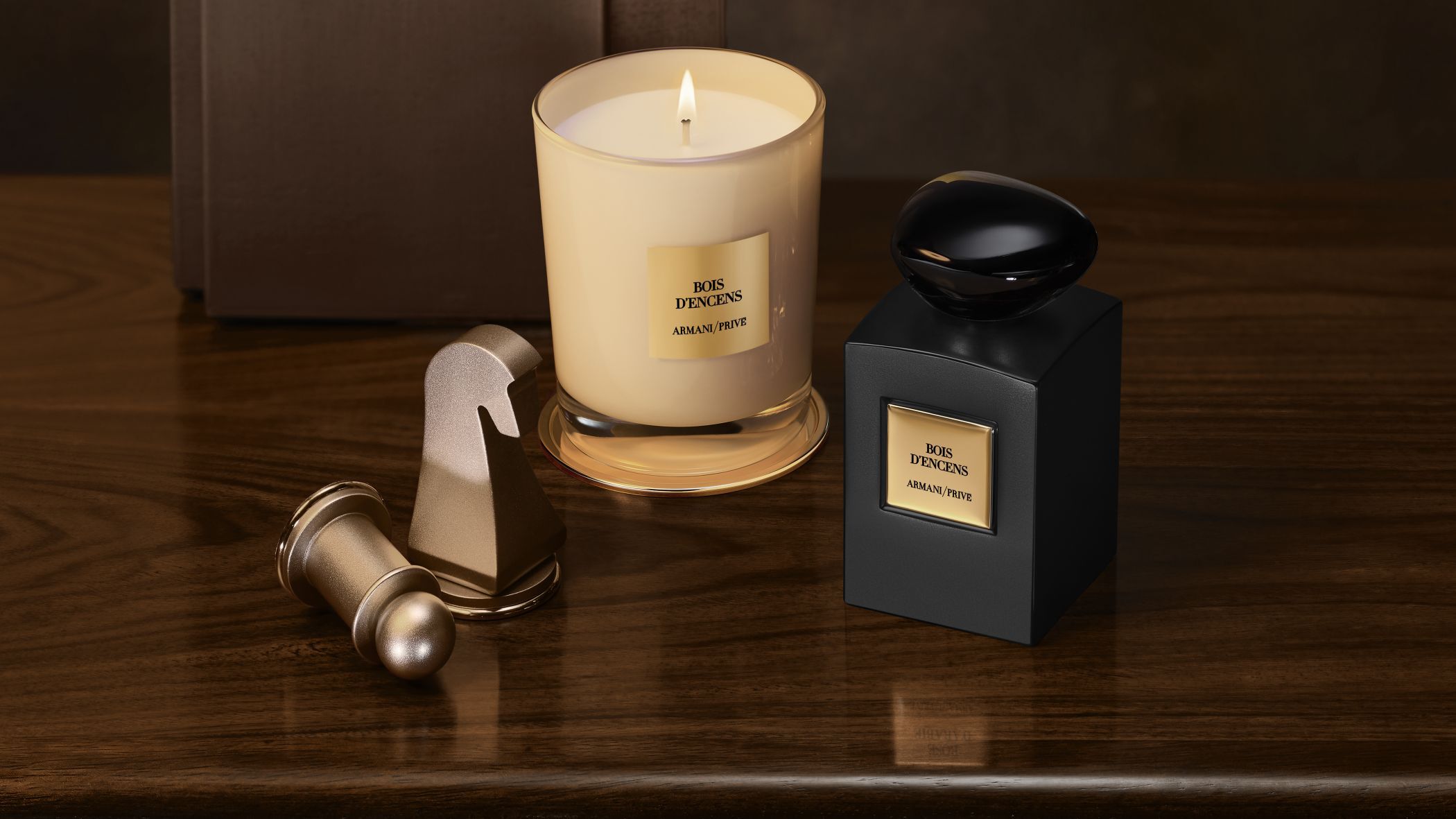 Armani/Prive Bois d'Encens Parfumflakon und brennende Kerze neben Schachfiguren auf einem Holztisch.