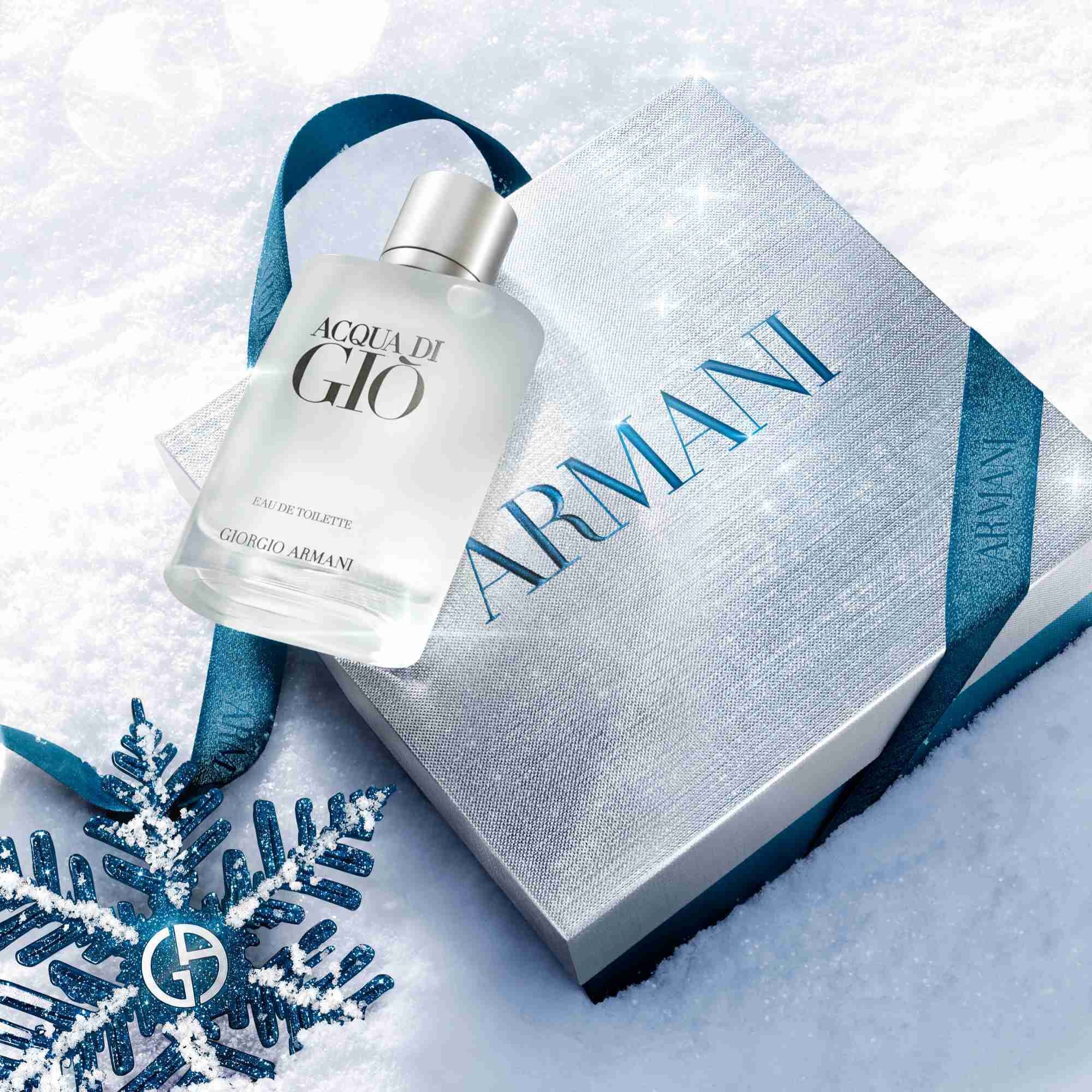 Acqua di Gio Eau de Toilette 50ml gift set in a silver Armani gift box with blue ibbon, styled on a snowy surface with a blue glitter snowflake — Giorgio Armani holiday fragrance gift for men.