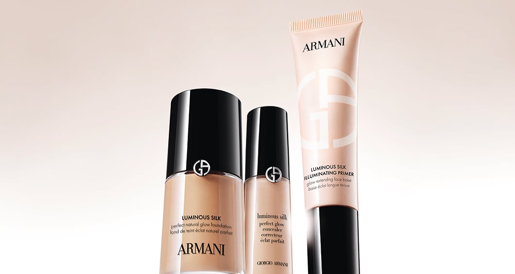 Zwei Flakons des Emporio Armani Parfüms „Stronger With You“ auf einem reflektierenden roten Hintergrund.