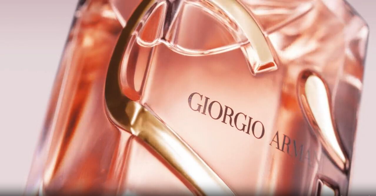 Close-up of a Giorgio Armani perfume bottle, featuring a sleek design and soft pink liquid inside.