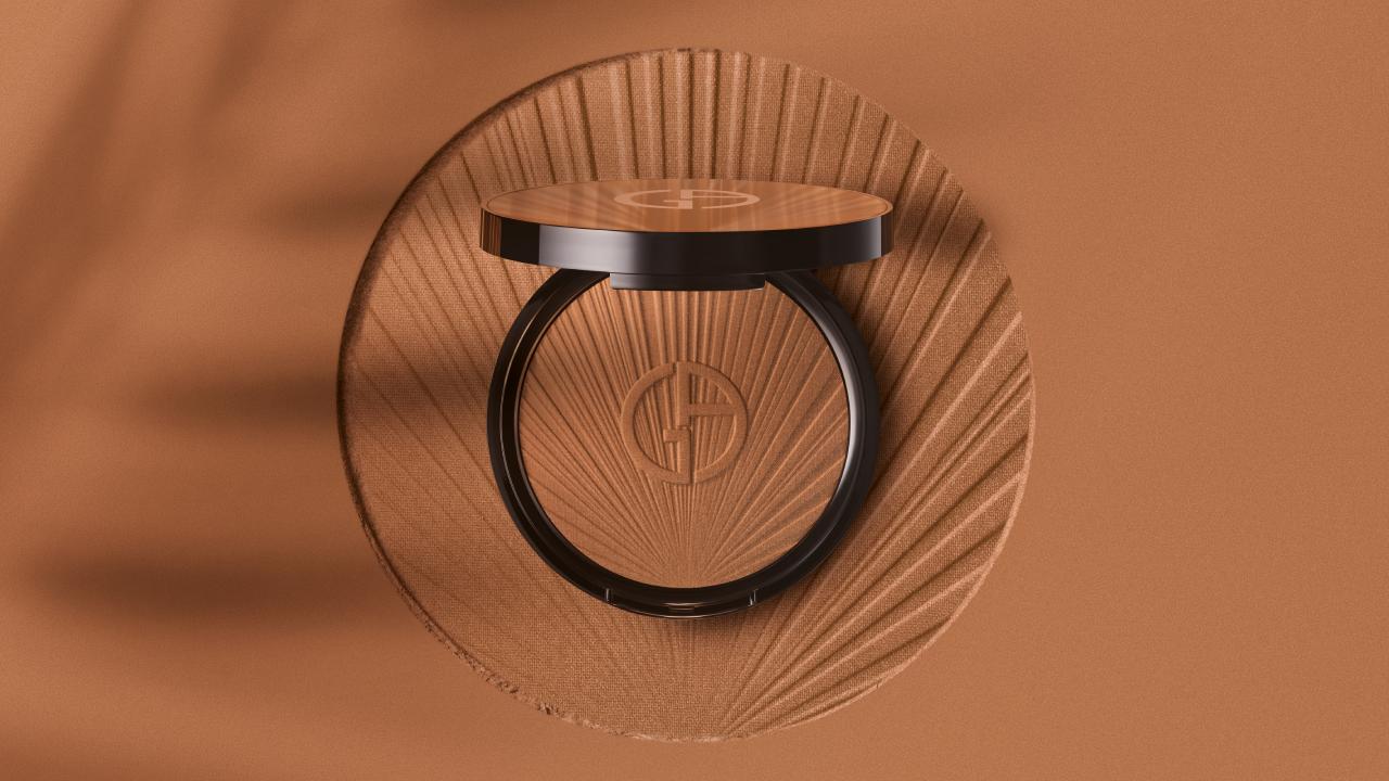 Ein elegantes Kompaktpuder mit einem runden Spiegel und dem Giorgio Armani-Logo, eingebettet in einem sandfarbenen Hintergrund.