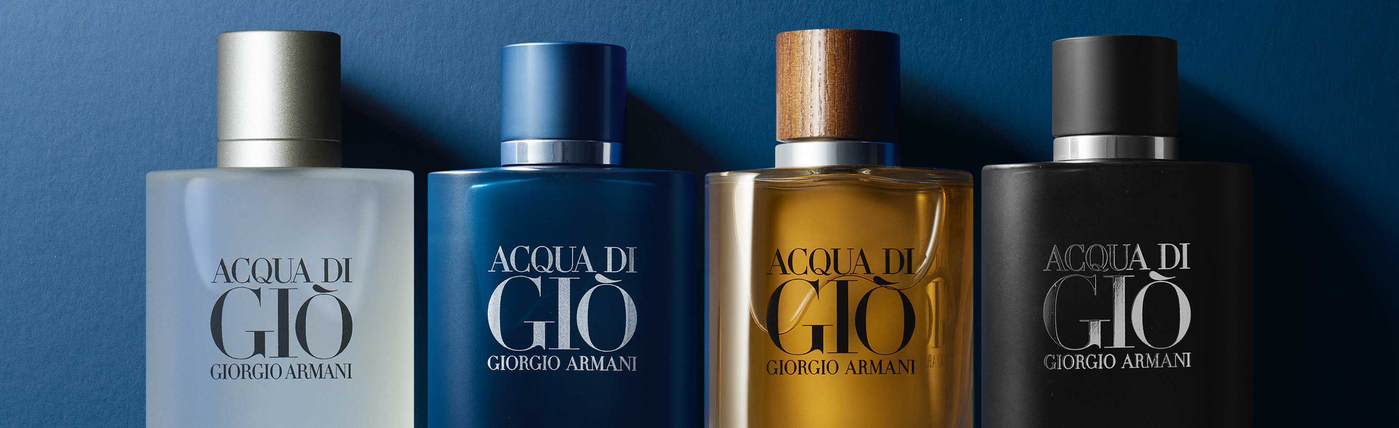 Four bottles of Acqua di Giò by Giorgio Armani, showcasing different scents with distinct colored labels against a blue background.